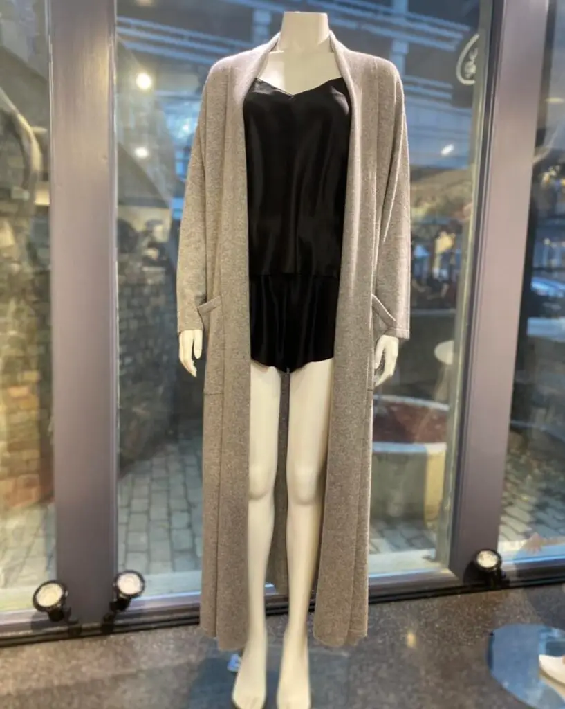 Gray cashmere robe draped over a mannequin wearing a black chemise, displayed in a boutique setting with soft lighting to emphasize the robe’s cozy texture and elegant style.